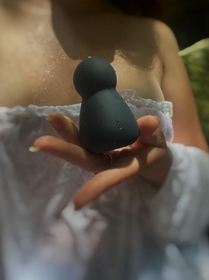 Young woman holding sooty vibrator in natural setting